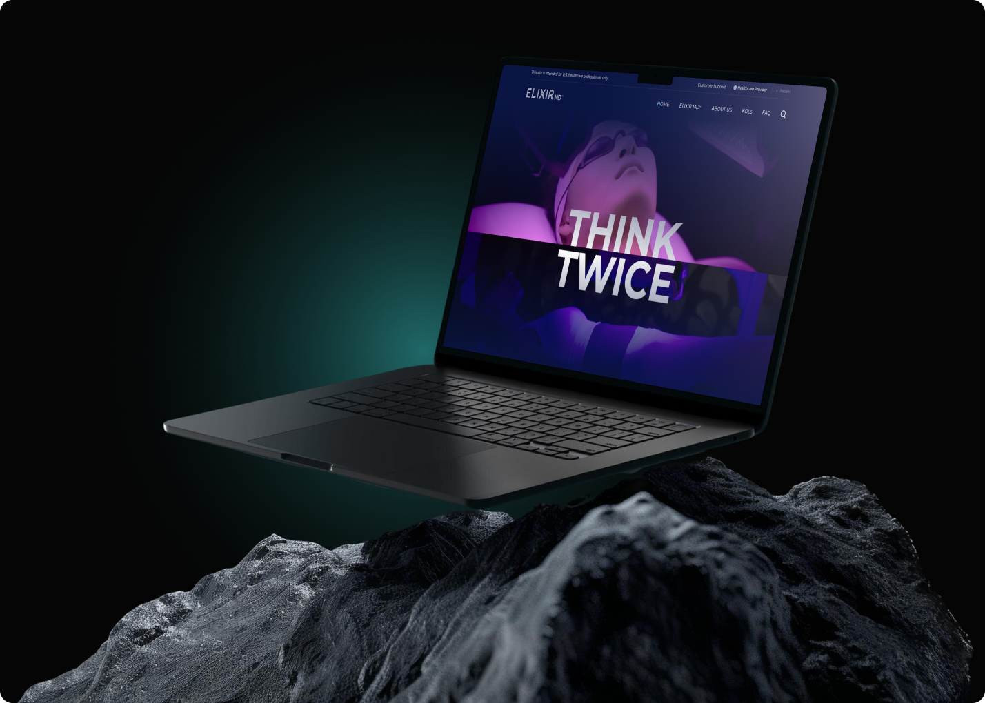 Laptop displaying creative work on a dark, rocky surface